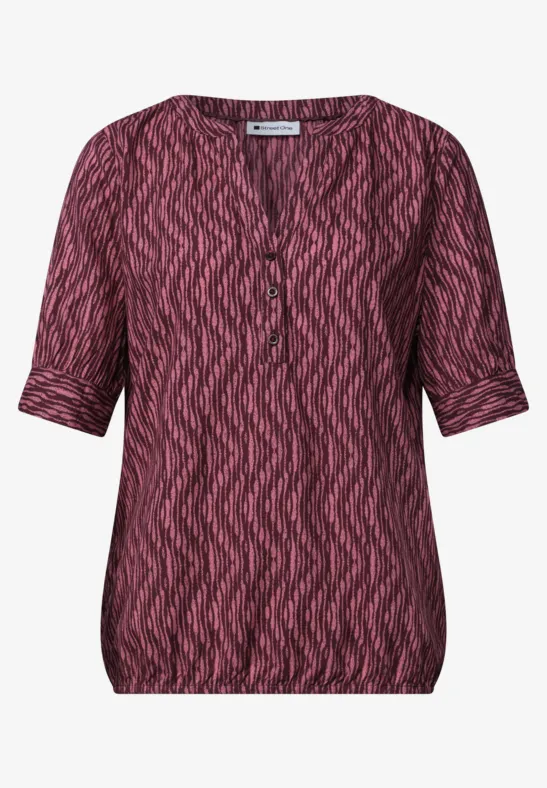 Damesblouse met korte mouwen, V-hals en roze-zwart zigzagmotief.