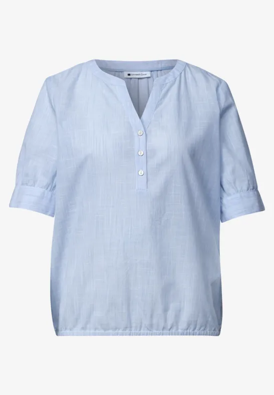 Hellblaue Bluse mit kurzer Knopfleiste, halblangen Ärmeln und elastischem Saum.