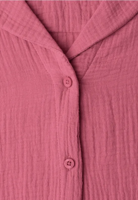 Nahaufnahme eines rosa, knitterigen Oberteils mit V-Ausschnitt und zwei Knöpfen.