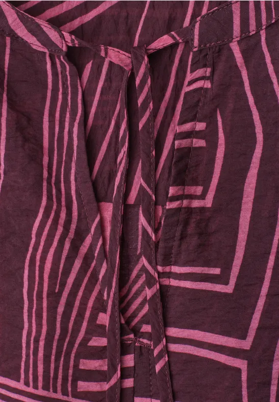 Donkerviolette stof met roze geometrisch streeppatroon en bindceintuur.