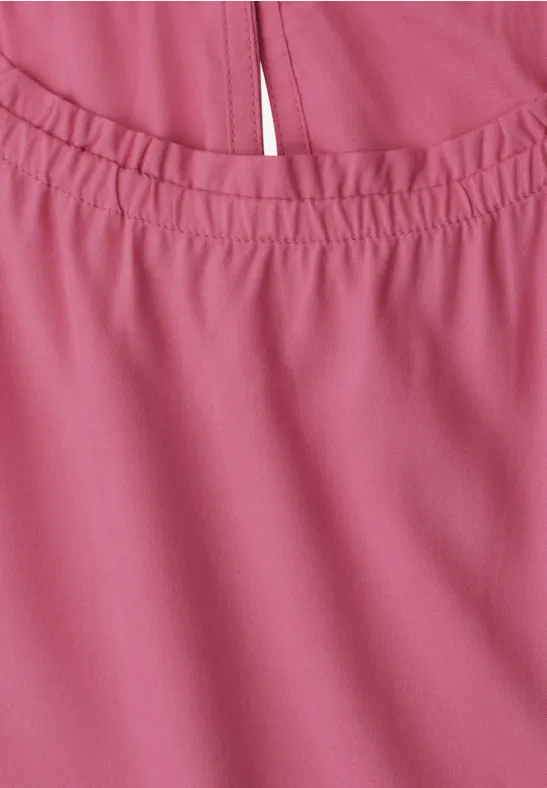 Nahaufnahme eines rosa Kleidungsstücks mit elastischem Ausschnitt und zierlicher Mittelnaht.
