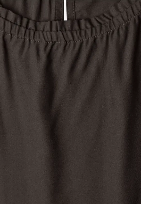 Nahaufnahme eines dunklen Kleidungsstücks mit elastischem Bund und seitlichem Schlitz.