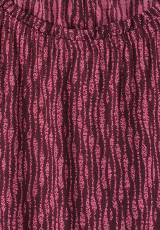 Gros plan d’un vêtement à motif ondulé rose foncé et noir, texture douce et léger froncé sur l'encolure.