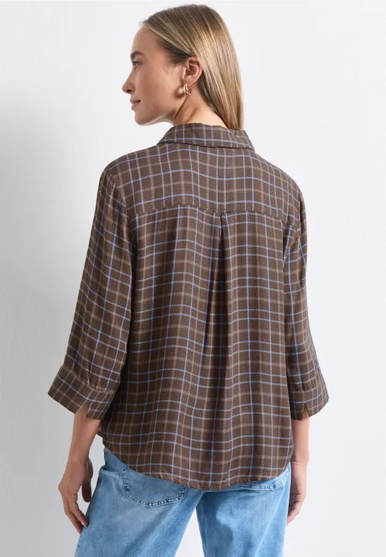 Frau von hinten in brauner karierten Bluse und Jeans.