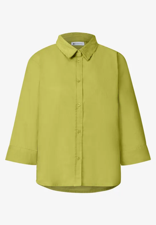 Eine hellgrüne, langärmelige Bluse mit Kragen und durchgehender Knopfleiste.
