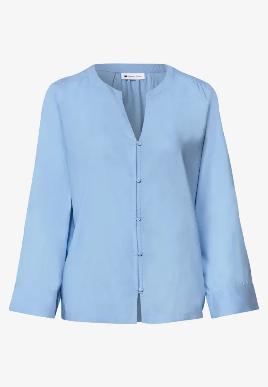 Hellblaue Bluse mit langen Ärmeln, V-Ausschnitt und durchgehender Knopfleiste.