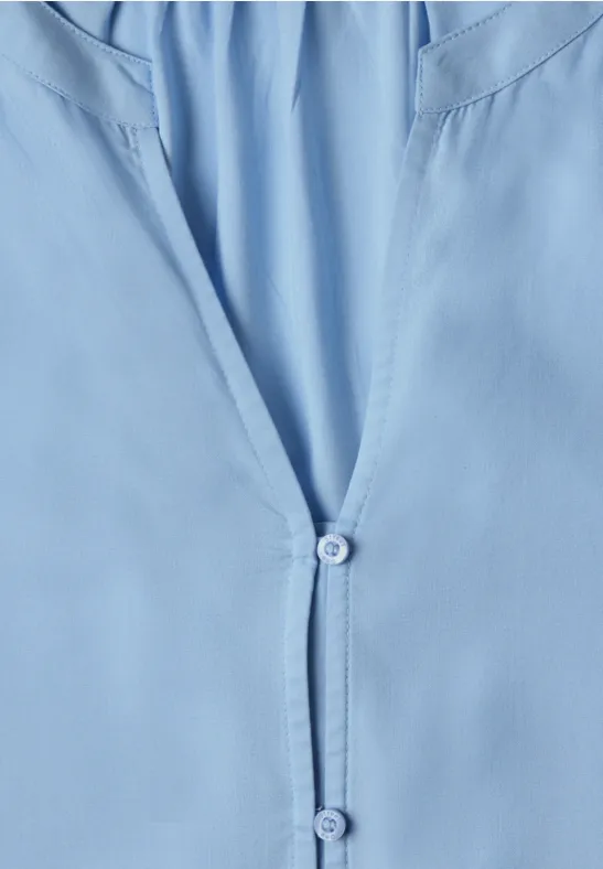 Hellblaues Hemd/Bluse im Detail, vorn leicht geöffnet mit zwei Knöpfen.
