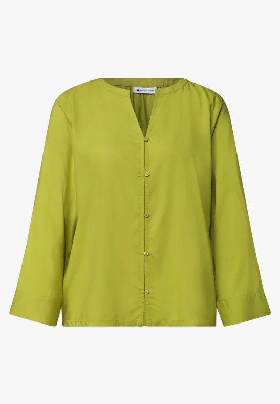 Blouse légère à manches longues vert vif, col en V et fermeture boutonnée.