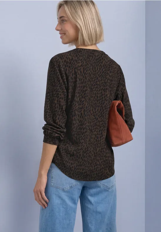 Frau von hinten, schwarzes Shirt mit braunem Leomuster, blaue Jeans, hält cognacfarbene Tasche.
