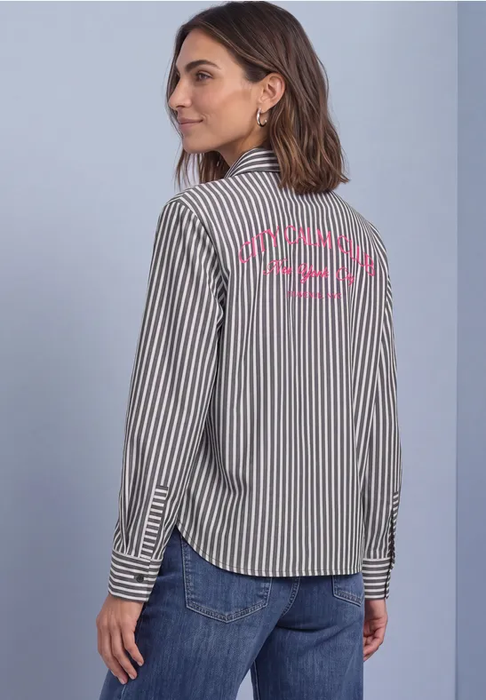 Une femme en chemise rayée noir et blanc et jean regarde par-dessus son épaule, texte coloré dans le dos.