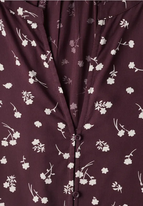 Dunkellila Bluse mit feinem weißen Blumenmuster, geknöpftem V-Ausschnitt und leichter Raffung.