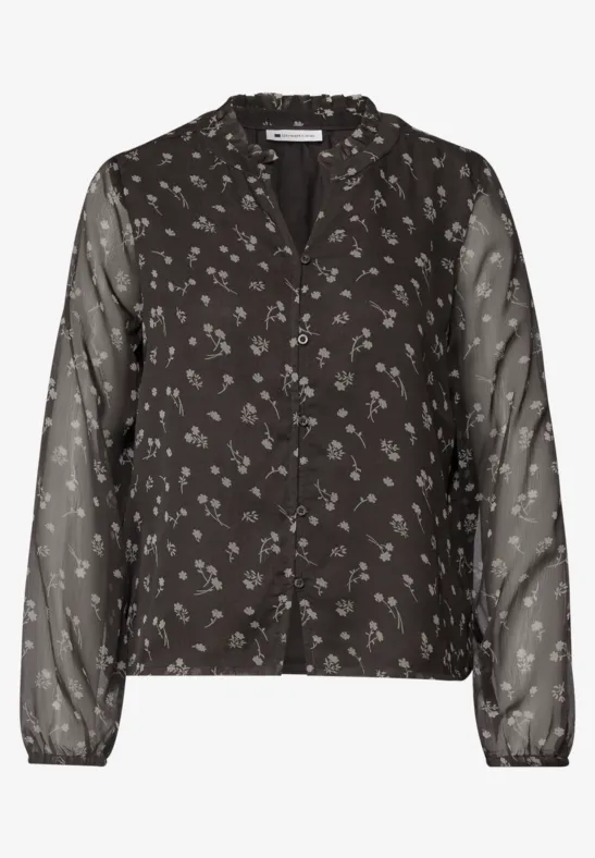 Zwarte blouse met knoopsluiting, klein wit bloemenprint en lange, transparante mouwen.