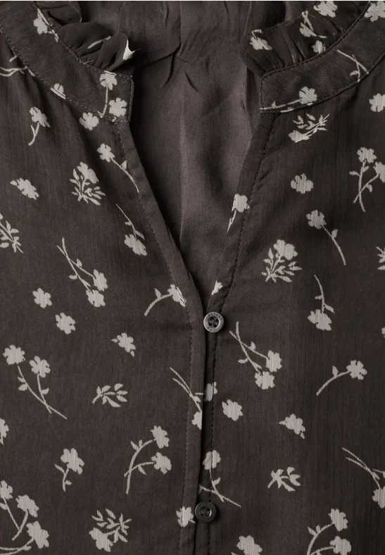 Zwarte stof met fijne witte bloemenprint en zwarte knopen.