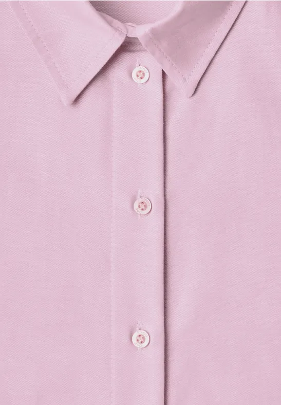 Nahaufnahme eines rosa Hemdkragens mit drei Knöpfen auf der Vorderseite.