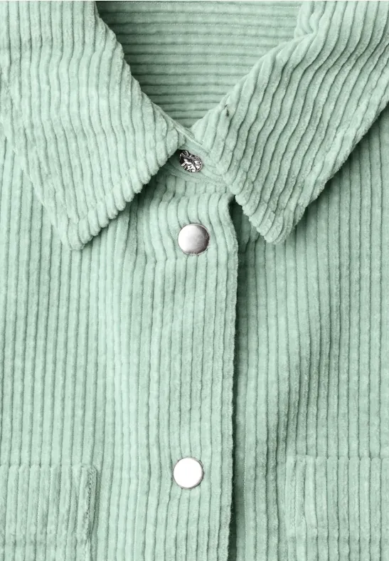Detailaufnahme eines mintgrünen Cordhemds mit Kragen und weißen Druckknöpfen.