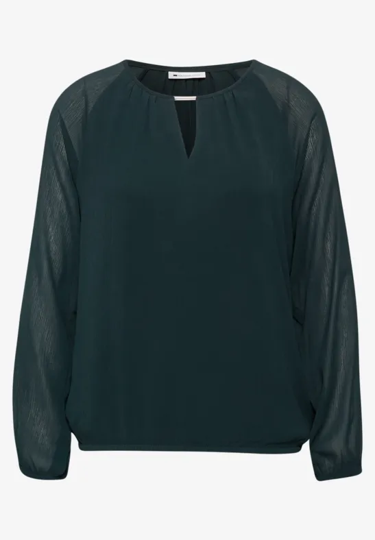 Donkergroene chiffonblouse met lange, transparante mouwen en kleine V-halsopening.