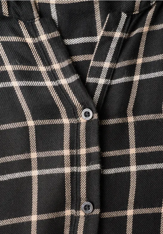 Nahaufnahme eines schwarz-beige karierten Kleidungsstücks mit zwei Knöpfen.