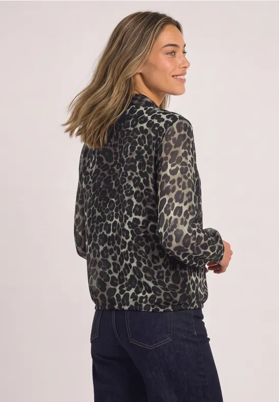 Eine Frau trägt eine leger geschnittene Jacke mit Leopardenmuster, von hinten fotografiert.