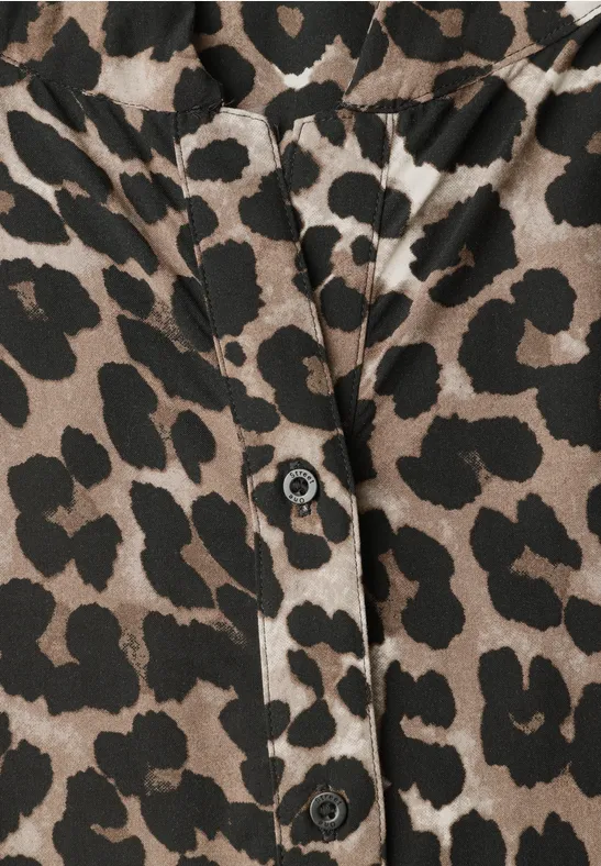 Nahaufnahme eines Kleidungsstücks mit Leopardenmuster und schwarzen Knöpfen.