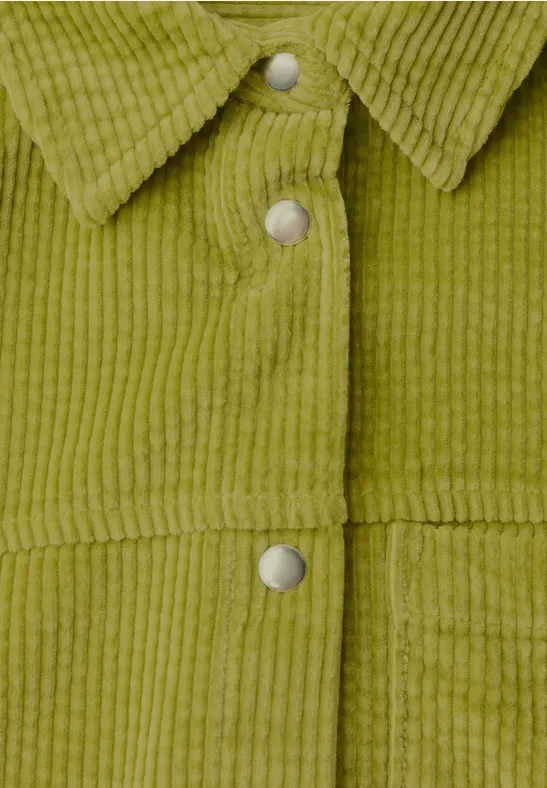 Nahaufnahme einer olivgrünen Cordjacke mit Stehkragen und silbernen Druckknöpfen.