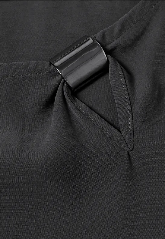 Nahaufnahme eines schwarzen Kleidungsstücks mit Tasche und integriertem schwarzen Metallring.