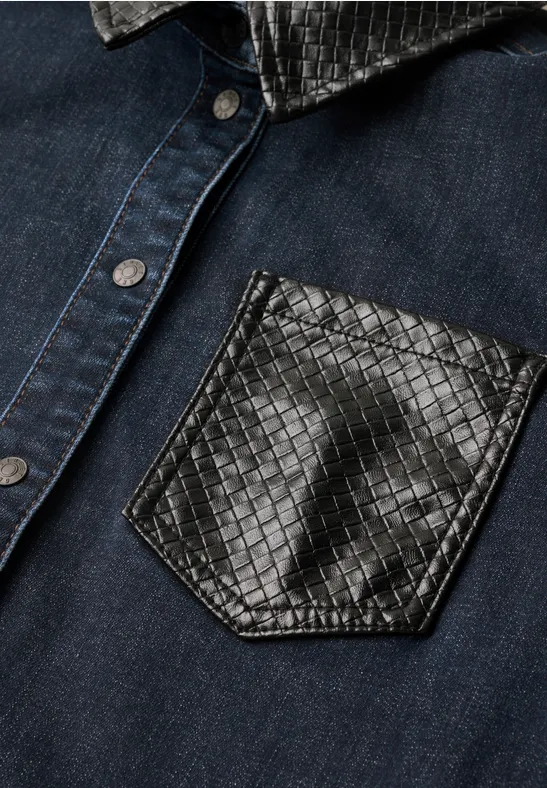 Dunkelblaue Jeansjacke mit glänzender, strukturierter schwarzer Lederbrusttasche.
