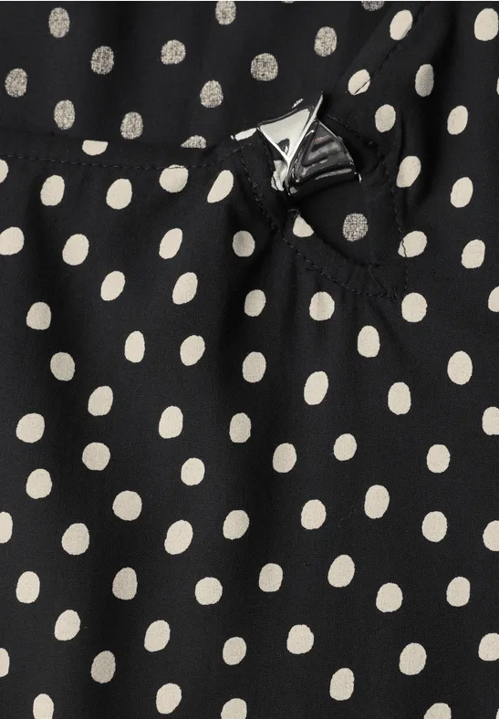Schwarzer Stoff mit weißen Polka-Dots und kleiner Zierschleife.