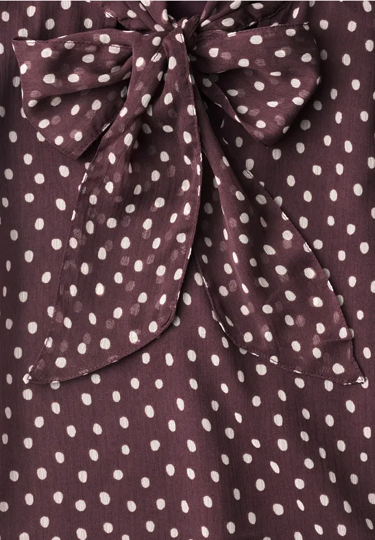 Tissu violet foncé à pois blancs avec un grand nœud.