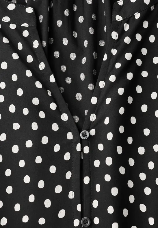 Schwarzes Kleidungsstück mit weißen Polka-Dots und V-Ausschnitt, vorn mit Knopfverschluss.
