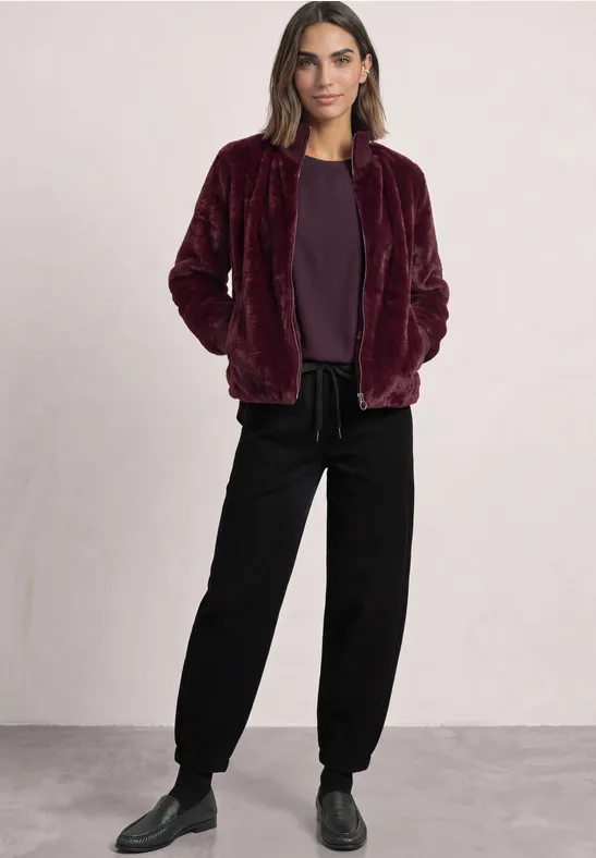 Femme portant une veste teddy bordeaux, tee-shirt assorti et pantalon noir ample
