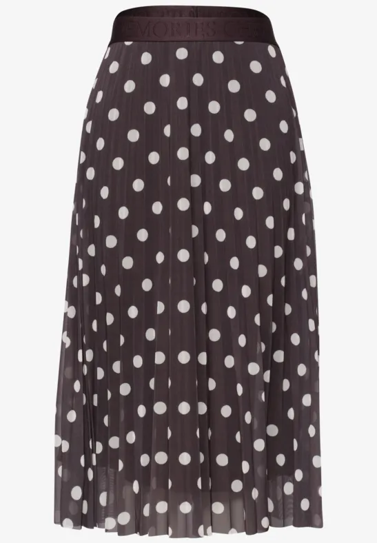 Une jupe mi-longue plissée marron foncé à pois blancs.