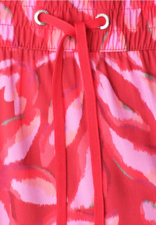 Rode stof met roze-witte abstracte patronen, elastische taille met rood koord en oogjes.