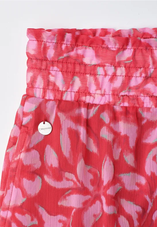 Rotes, geblümtes Kleidungsstück mit gerafftem Bund und rundem Metall-Emblem