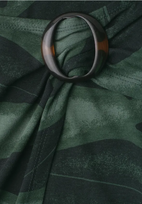 Dunkelgrüner, gemusterter Stoff, elegant mit ringförmigem Halter drapiert.