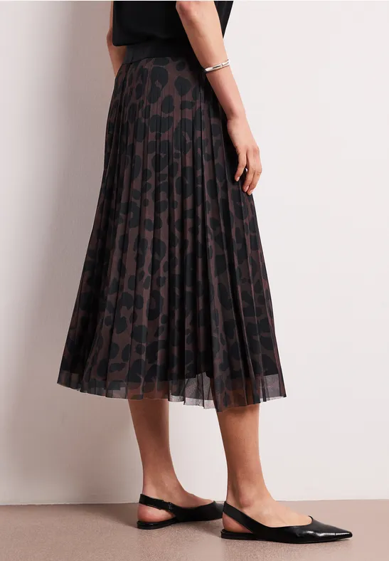 Donkere geplisseerde midirok met luipaardprint, gecombineerd met zwarte slingback pumps.