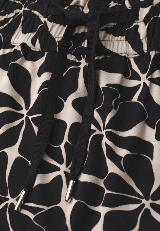 Schwarz-beige Stoff mit abstraktem, großblättrigem Blumendruck und elastischem Bund mit Kordelzug.