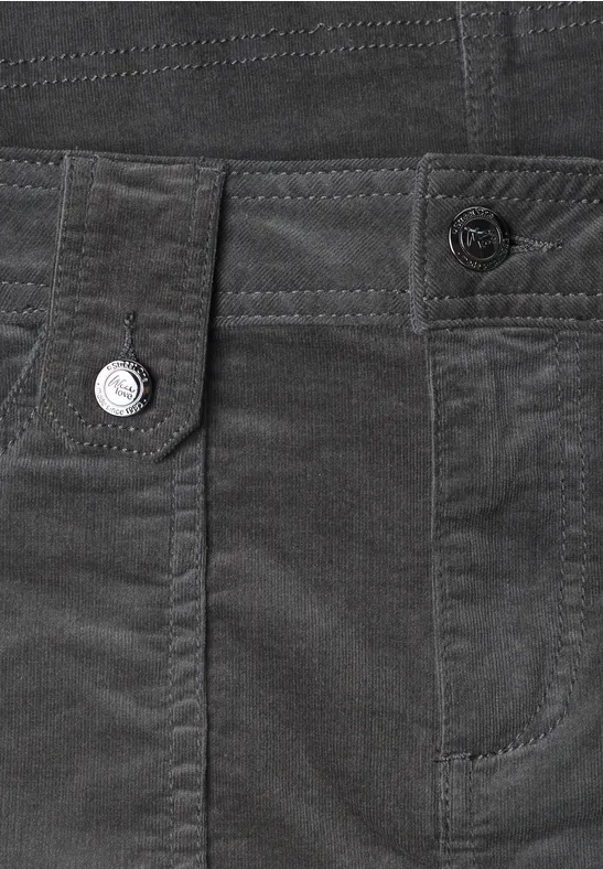 Close-up van een donkergrijze corduroy broek met zakken, riemlussen en knoopdetail.