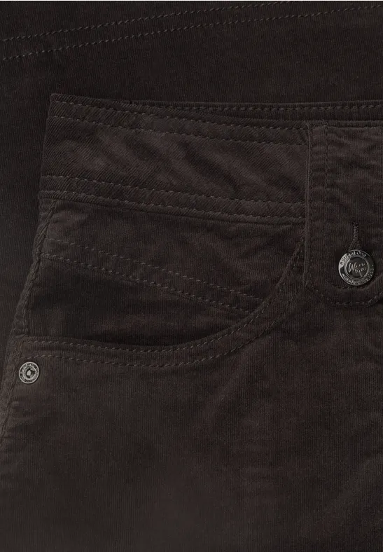 Close-up van een bruine ribfluwelen broek met zakken en sierstiksels.