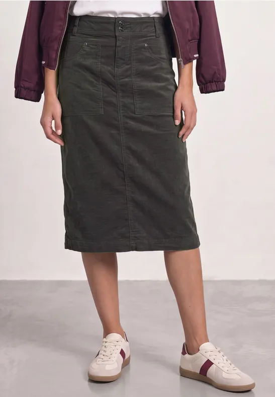 Dunkelgrüner Cord-Midirock mit geradem Schnitt, hoher Taille und seitlichen Taschen, kombiniert mit Sneakern.