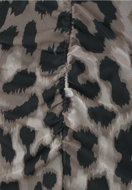 Close-up van een stof met beige-zwarte luipaardprint en zichtbare middennaad.