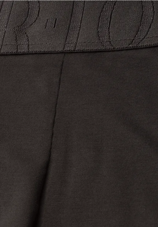 Gros plan sur un tissu noir avec couture et ceinture élastique.
