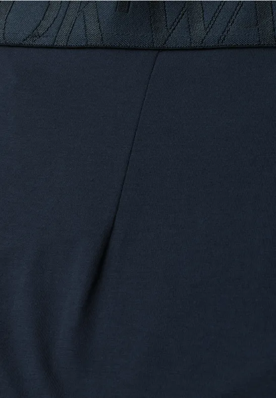 Close-up van een donkerblauwe, nauwsluitende legging met hoge taille en zichtbaar Nike-logo op de band.