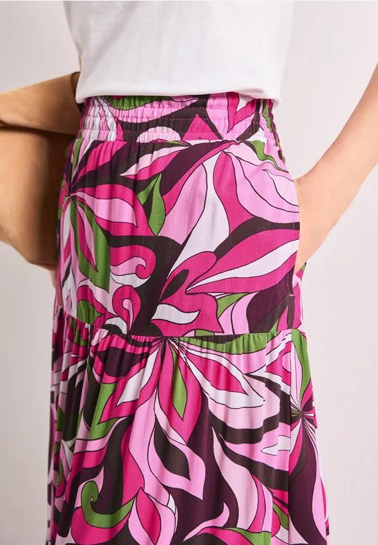 Lang geschnittener Rock mit elastischem Bund und auffälligem psychedelischem Muster in Pink, Lila und Grün.