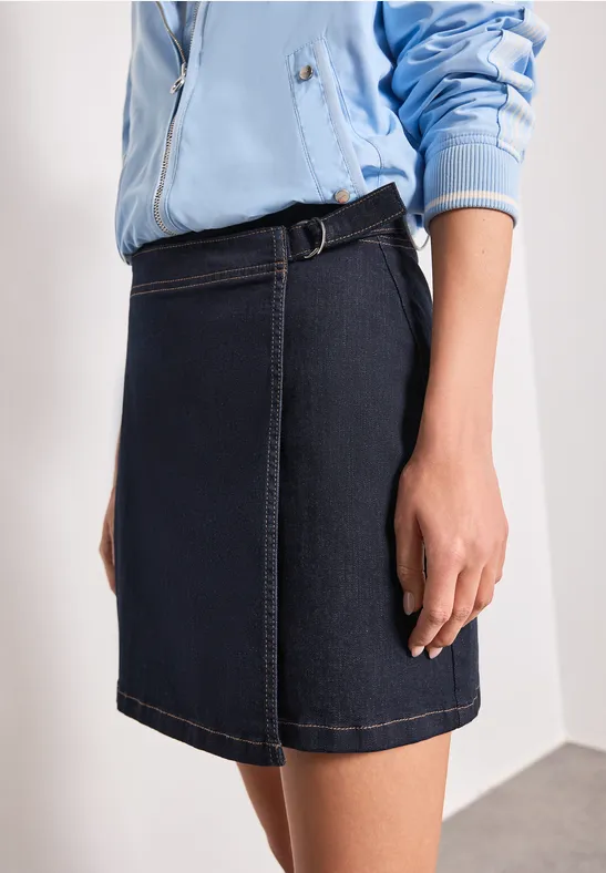 Korte donkerblauwe jeansrok met ceintuurlus, gecombineerd met een lichtblauwe jas