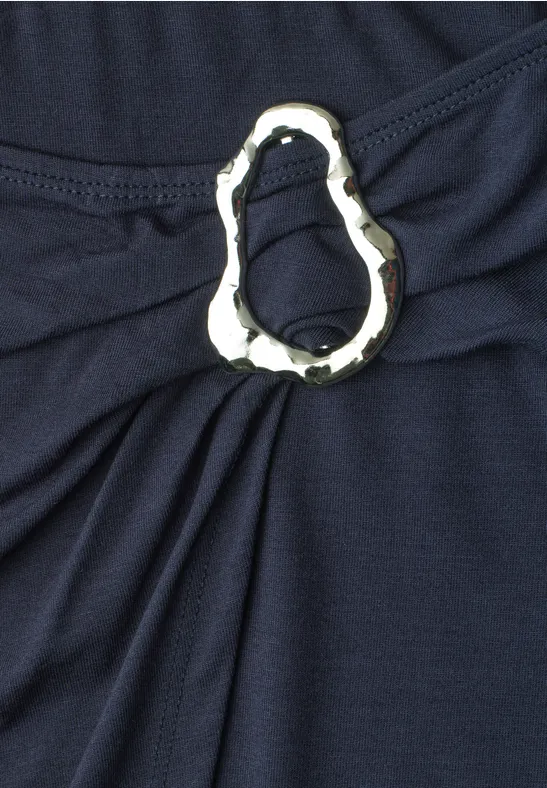 Dunkelblauer Stoff mit silbernem, dekorativem Ring, der Falten bildet.