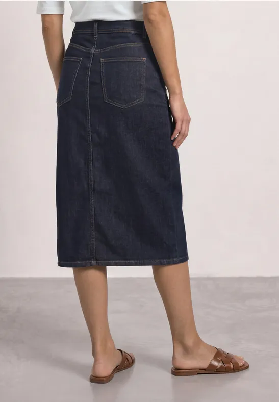 Dunkelblauer Jeans-Midirock mit Rückenschlitz und Taschen, dazu braune flache Sandalen.