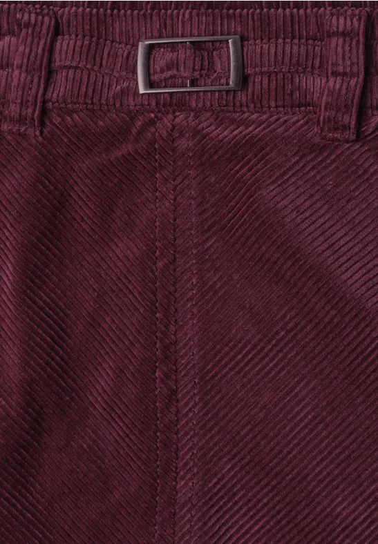 Nahaufnahme einer weinroten Cordhose mit Gürtel und feinem Rippenmuster