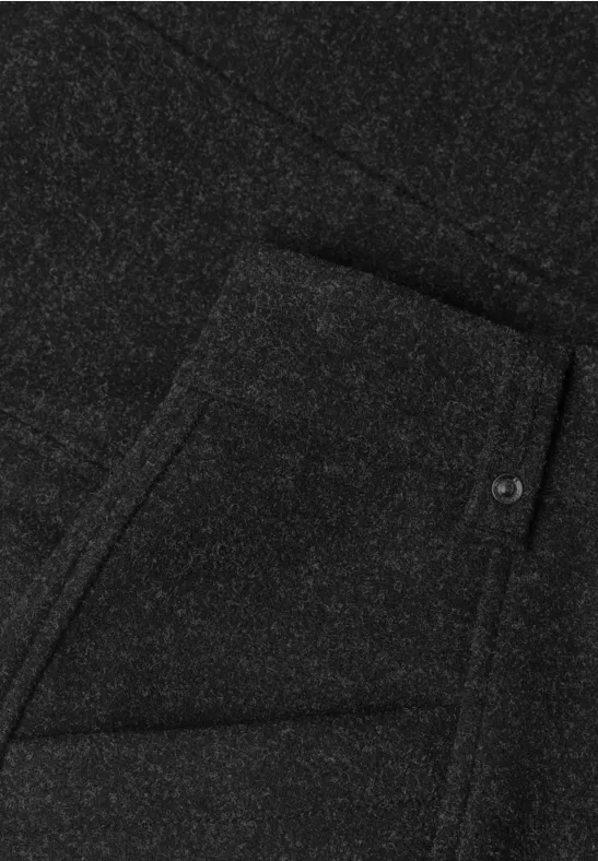 Schwarzer Stoff mit aufgesetzter Tasche, schräger Eingriff und Knopfdetail.