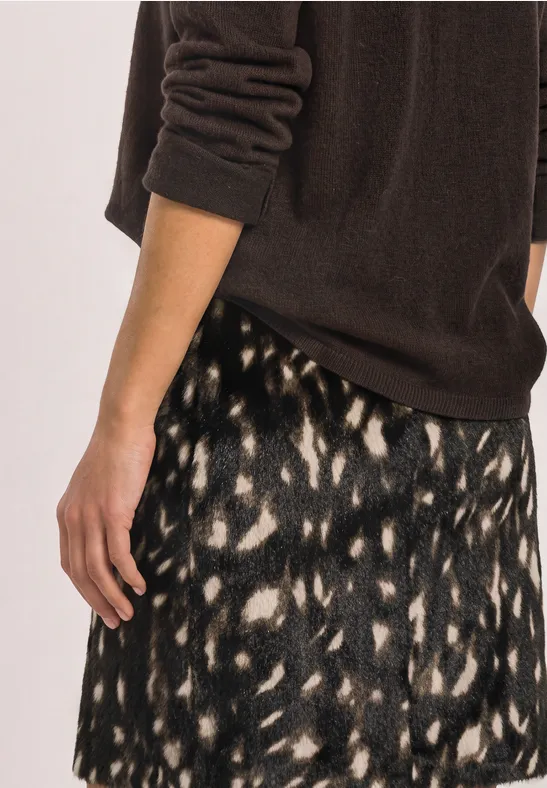 Frau trägt braunen Pullover und gemusterten Rock in Schwarz und Creme mit abstraktem Leopardenmuster.