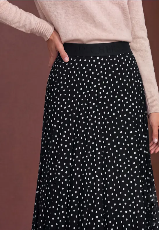Schwarzer, weit schwingender Rock mit weißen Polka Dots, kombiniert mit leicht rosafarbenem Oberteil